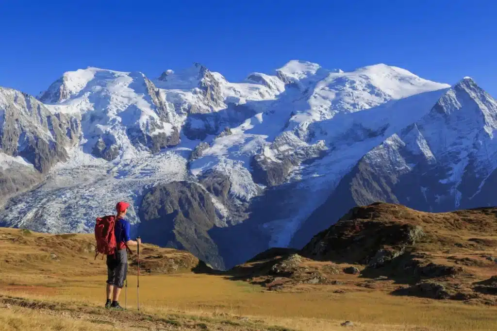 Wandelaar in een weiland kijkend in de richting van de Mont Blanc, tijdens zijn wandeltocht van de Tour du Mont Blanc.